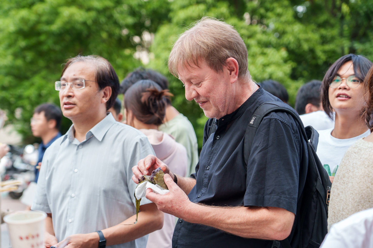 一名外国教授尝试黑米粽子（学通社记者 韩鑫垚 摄）