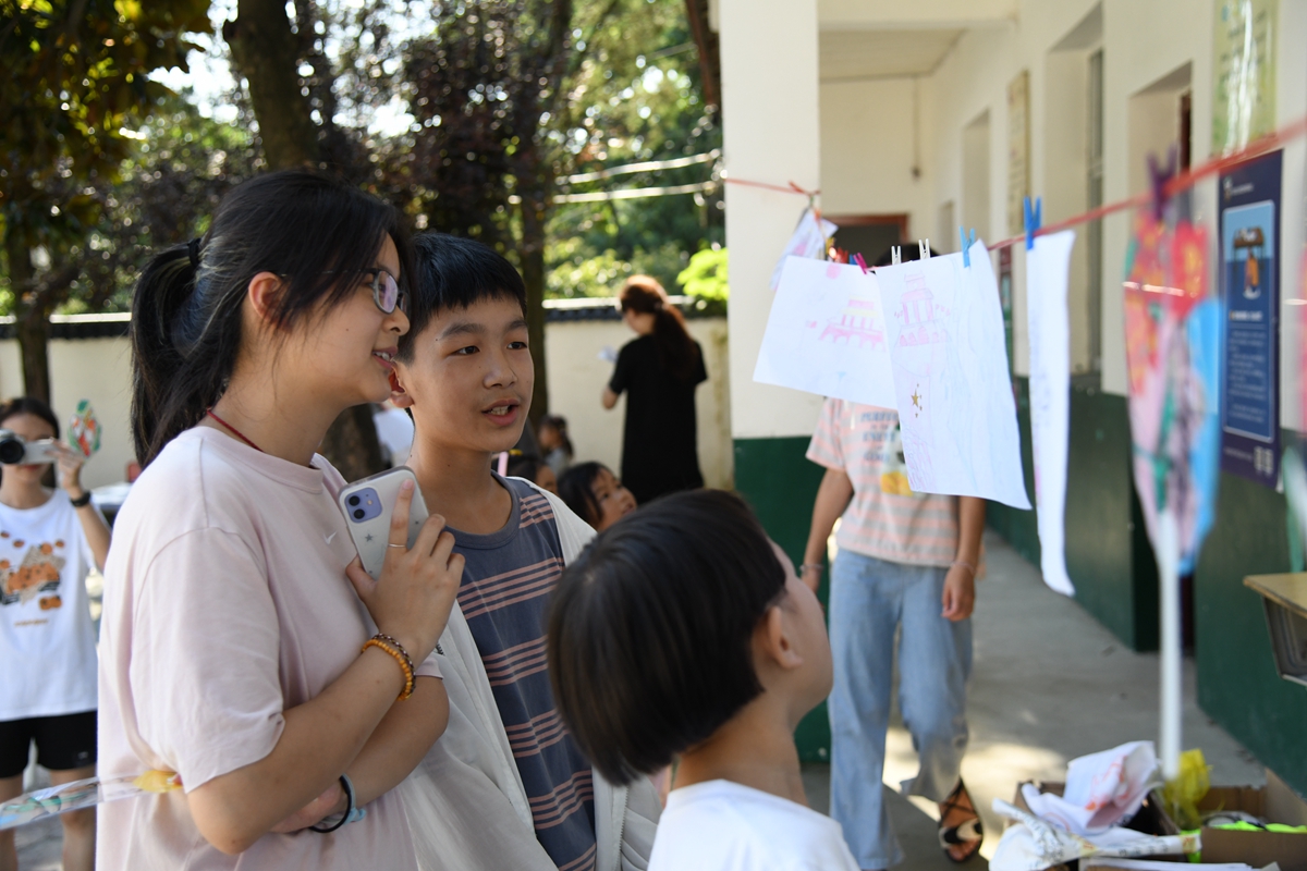 郑宇涵同学向支教队员介绍自己的作品（通讯员 徐行 摄）