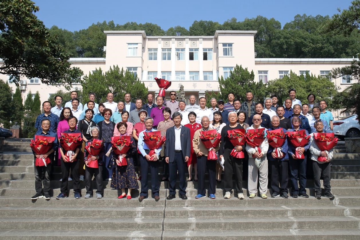 (高翅与校友代表、退休教师等在主楼前合影)