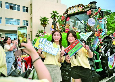 6月21日,华中农业大学学生在农机花车前拍照留念。新华社记者 程敏摄