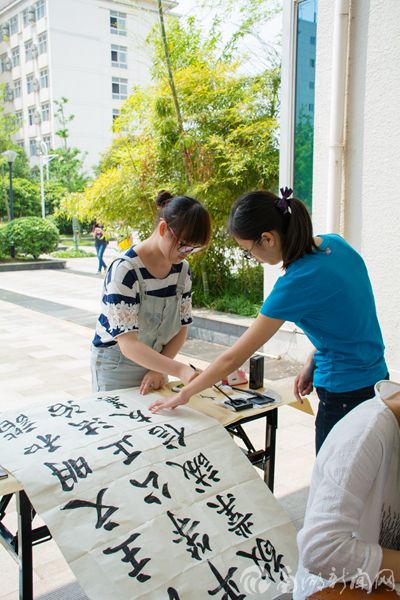 在小伙伴的帮助下参赛选手更好的完成着书法作品