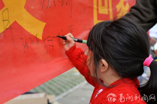 小孩在标语上耐心签上自己名字